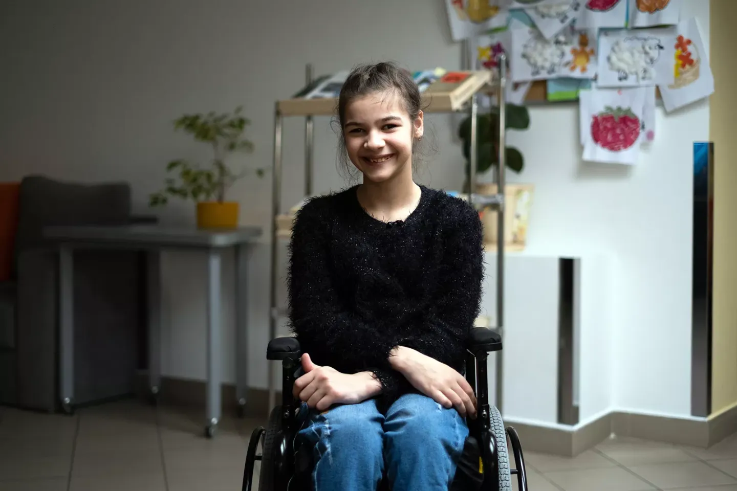  A smiling teenage girl sitting on a wheelchair.