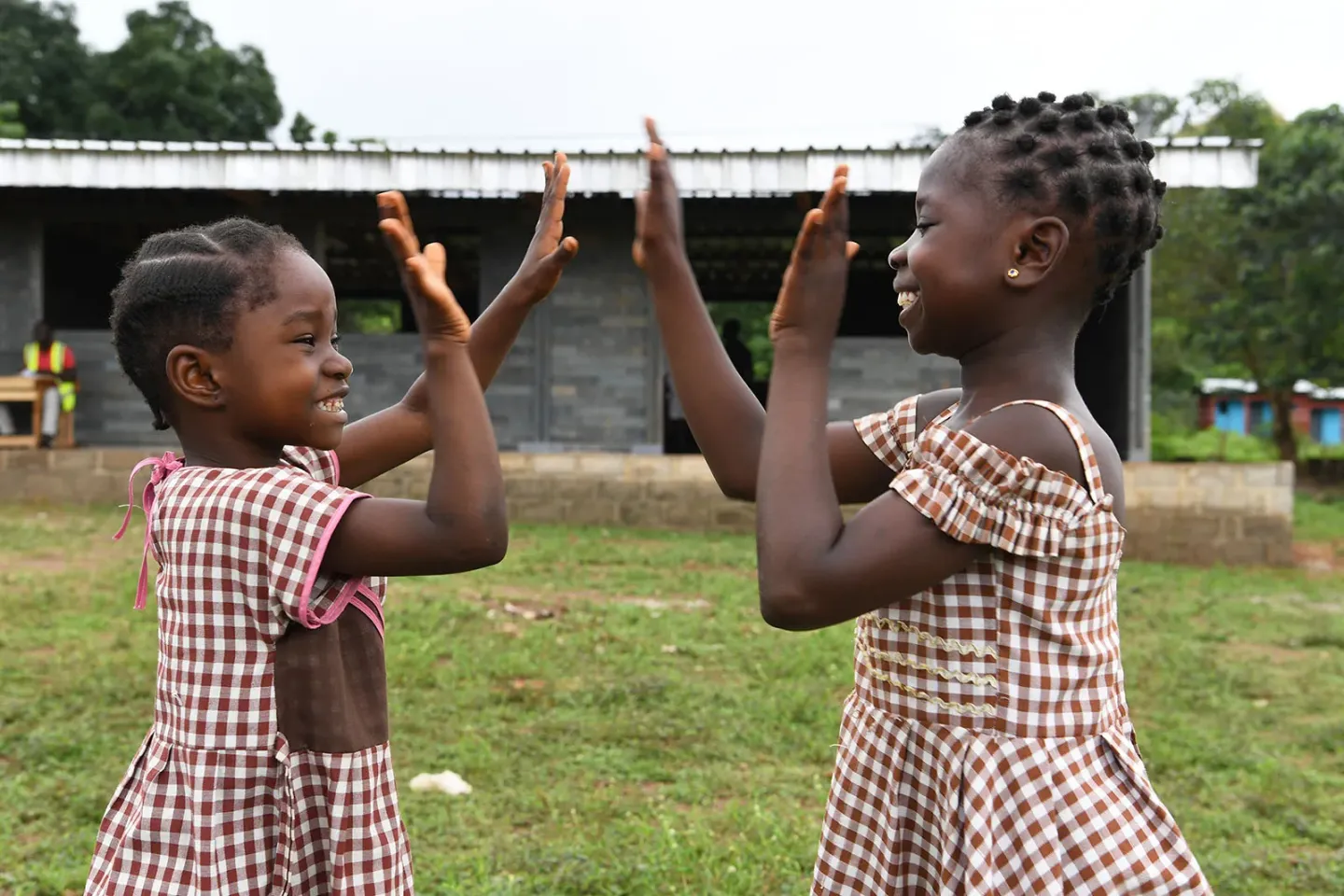 Two smiling girls play in front of their new school built with plastic bricks made out of recycled plastic, in Sangouine, a village in the West of C&ocirc;te d'Ivoire.