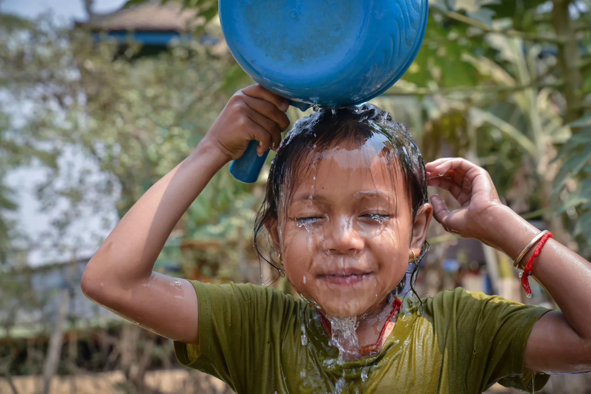 In Cambodia, Mara, 5, uses a cooking pot for her shower after school. 