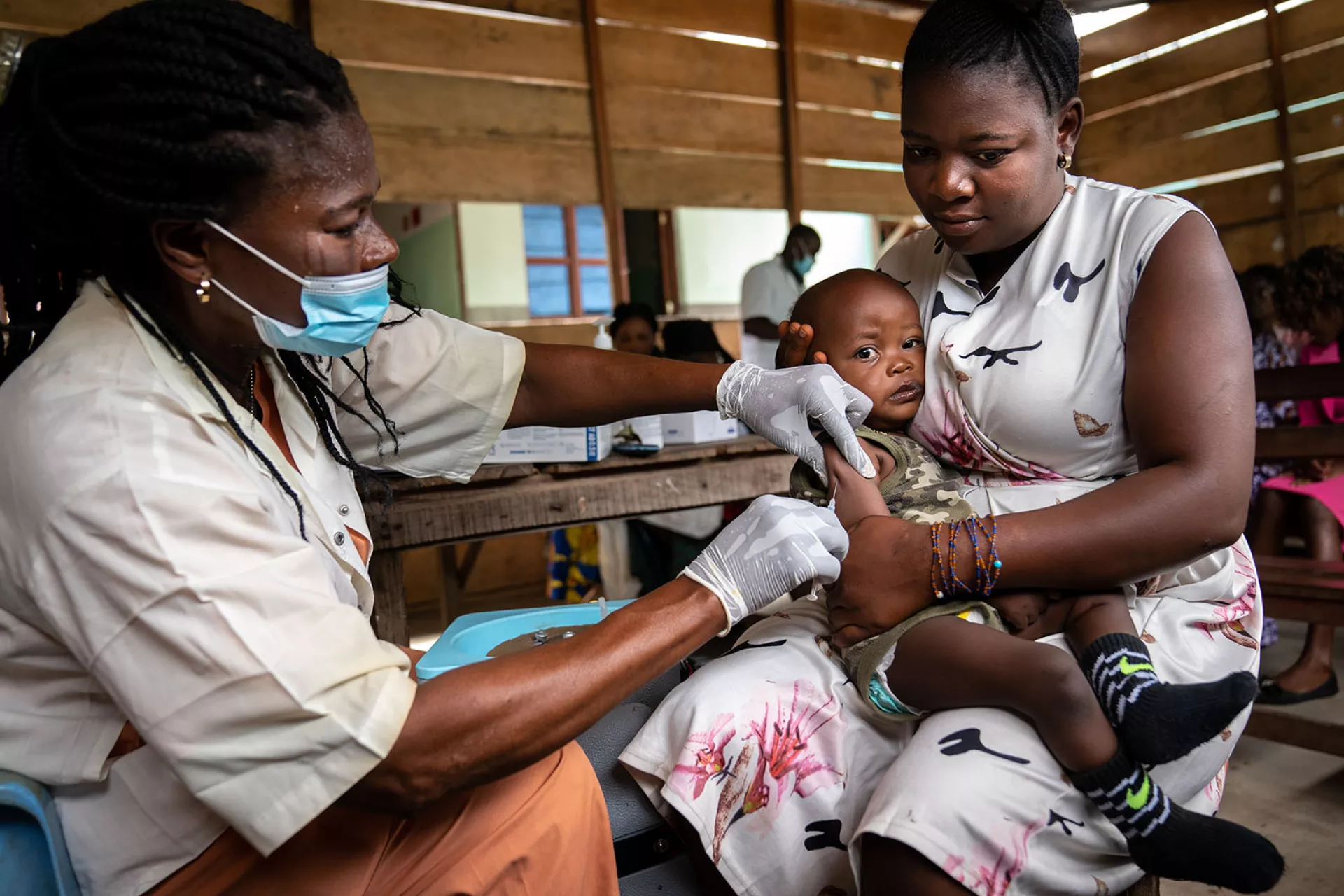 A mother holds her son as he receives yellow fever vaccine
