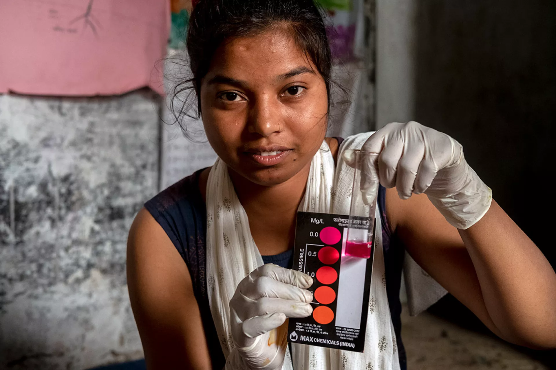 Woman showcases a water quality testing kit in action.