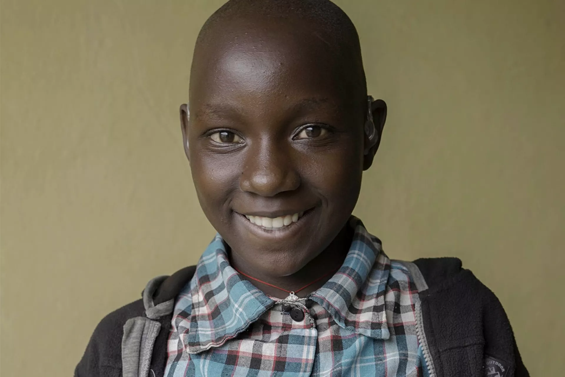 Pascaline smiles after testing her hearing aids for the first time, speaking easily with her mother.