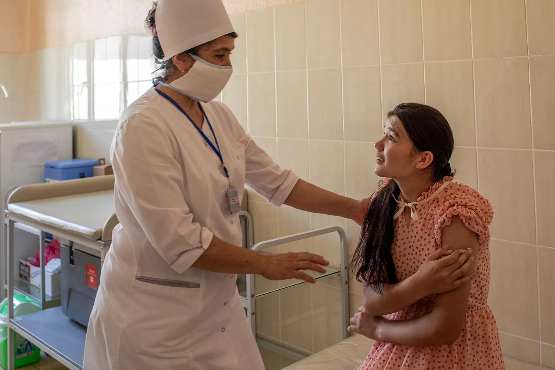 A girl holding a piece of gauze in her arm after receiving a dose of vaccine