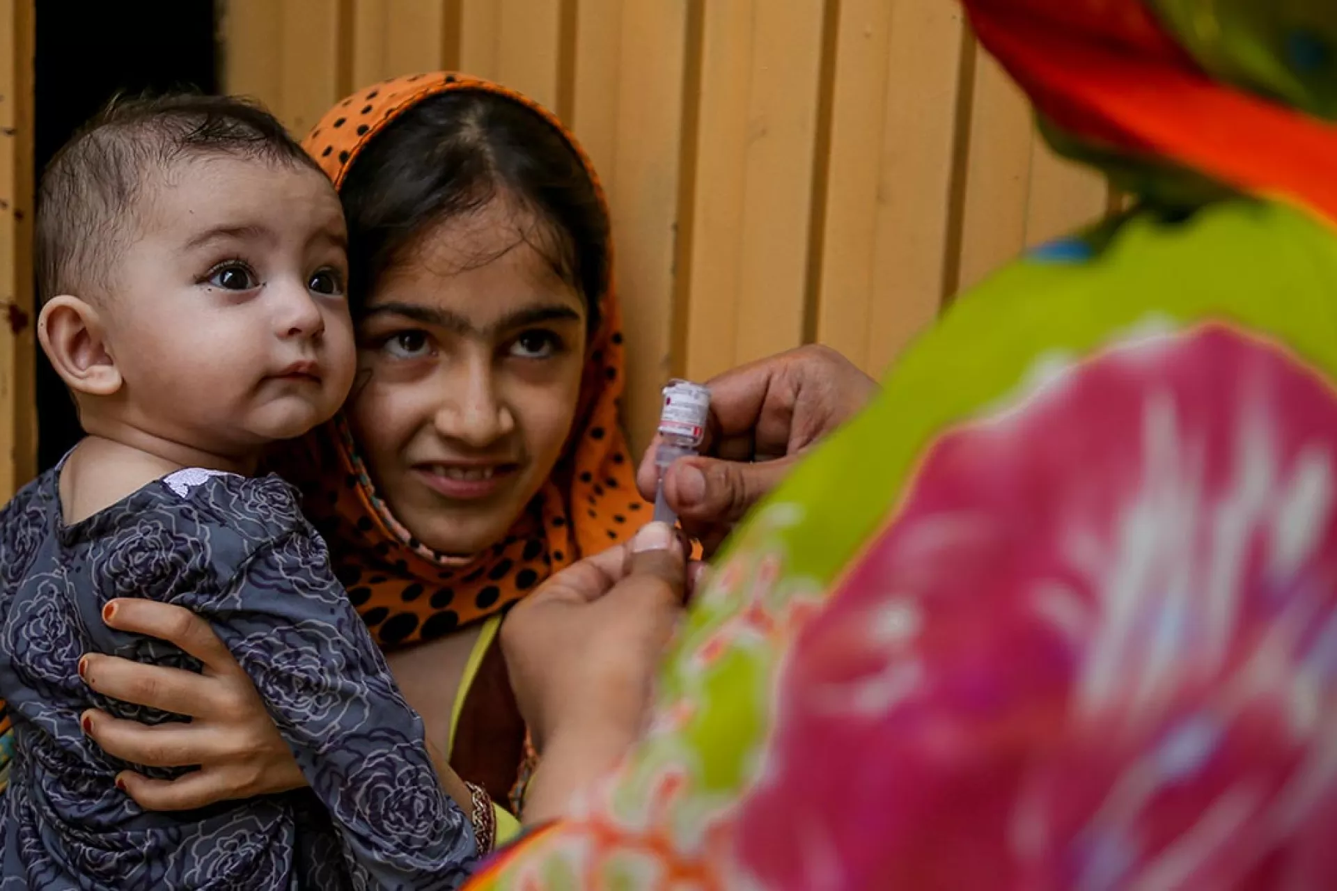 In 2017 in Khyber Pakhtunkhwa, Pakistan, a frontline health worker prepares to immunize a baby against polio in Shahin Muslim Town in Peshawar District.