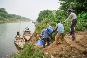 Health workers loading a canoe with vaccine carriers.