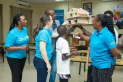 A boy surrounded by UNICEF staff showing a cardboard house.