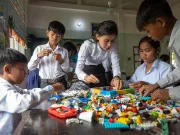 A teacher and her schoolchildren playing with LEGO bricks.
