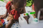 A child has her arm measured with the child arm circumference by the MUAC tape.