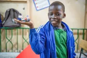 A schoolboy showing his work made with LEGO bricks.