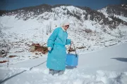 Health worker stepping through snow during a immunization campaign.