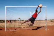 A person jumping to catch a ball in a football field.