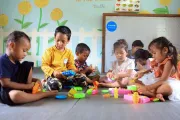 Several children play with plastic toy brics while sitting  on the floor.