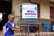 A child washing their hands with water from a container.