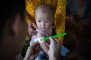 A child has her arm measured with the child arm circumference by the MUAC tape.