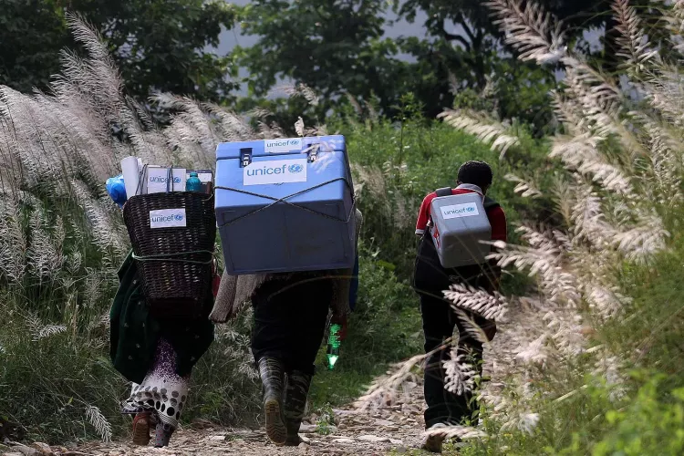 Three people carrying UNICEF-provided vaccines on difficult terrains on the way to a vaccination campaign to be conducted in Gorkha District, Nepal, the epicentre of the 2015 earthquake.