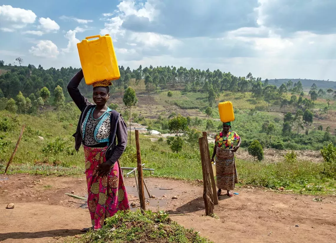 Two women carrying jerrycans on their heads.