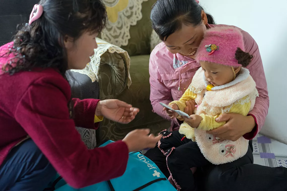 Family doctor Dr. Ri Chol Ok and child in her mother's arms. 