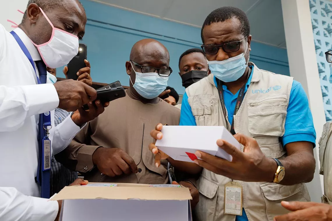 Dwomoh Ankrah, Ghana Health Services National Vaccine and Cold Chain Manager (left) and Arthur Osuji, UNICEF Ghana Supply Manager (right) examine a box containing the first shipment of COVID-19 vaccines distributed by the COVAX Facility.