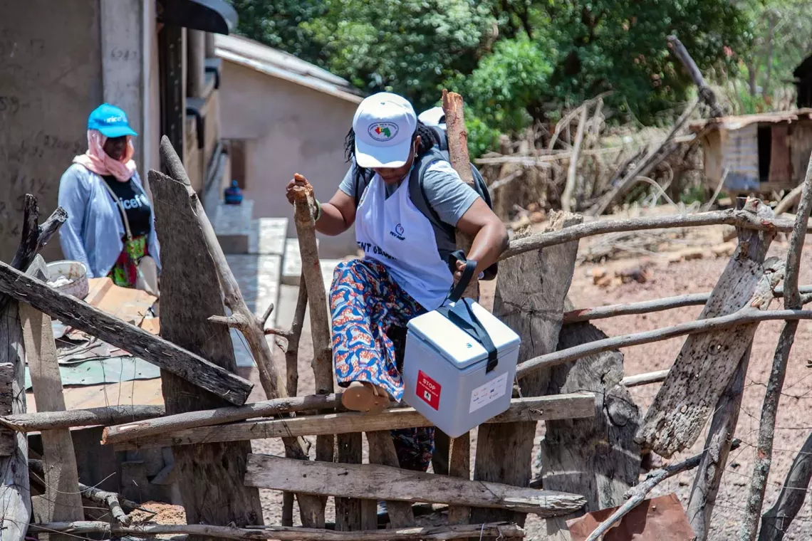 A woman climbs over a wooden makeshift fence. 