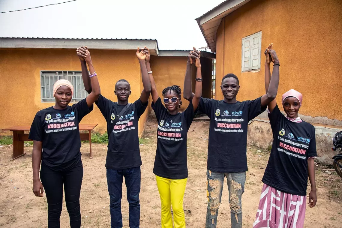 A group of five young people raise and hold their hands together. 