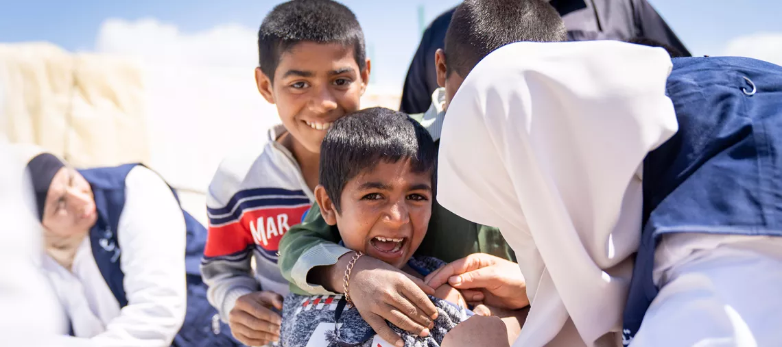A eight-year boy is vaccinated by a mobile health team in an informal tented settlement near the Dead Sea in Jordan, in April 2019. 