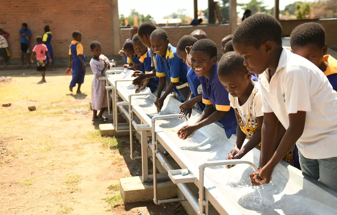 A group of boys washing their hands in an outdoor sink at Mchoka Primary School.