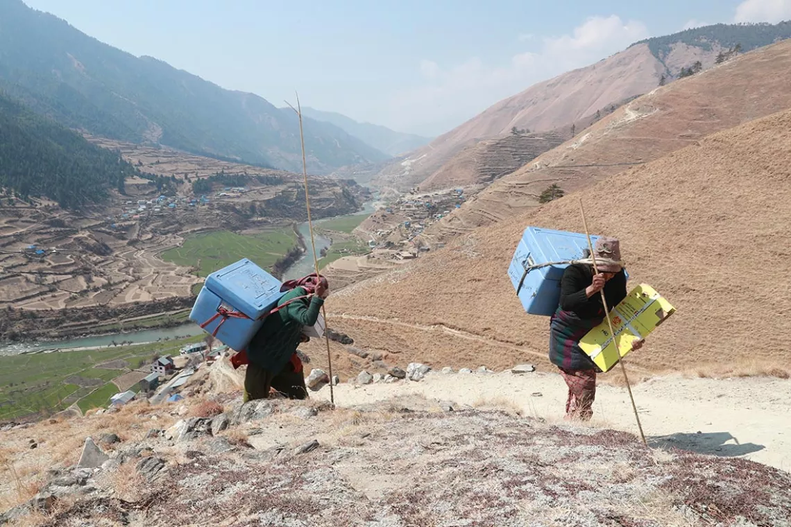 Using cold boxes provided by UNICEF, porters carry COVID-19 vaccines to health facilities in Jumla District in far-western Nepal, in March 2021.