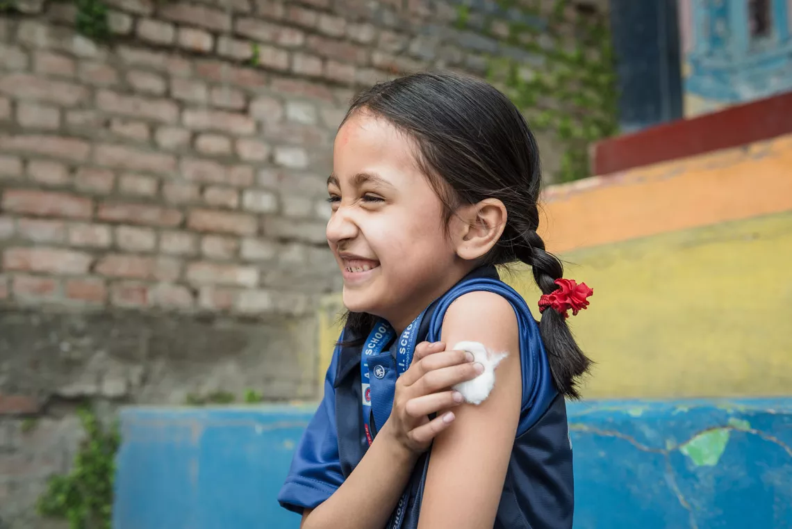 A girl presses cotton wool onto the injection site after a vaccination. 