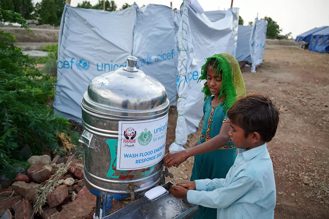 Eight-year-old Geetu shows her brother how to properly wash hands using soap, outside a public toilet in Pakistan.