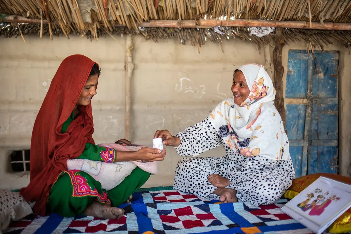 A healthcare worker distributes an MMS bottle to a woman in a community setting.