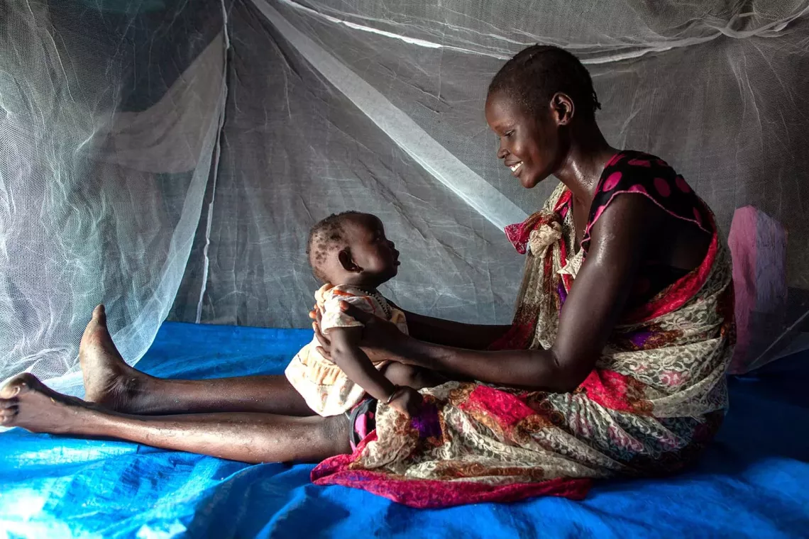 A woman and a baby under a mosquito net. 