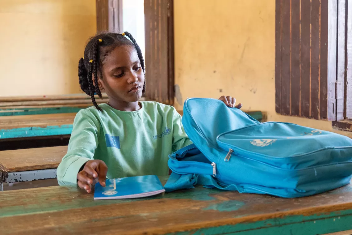 Wisam looks through her backpack while sitting in the classroom. 