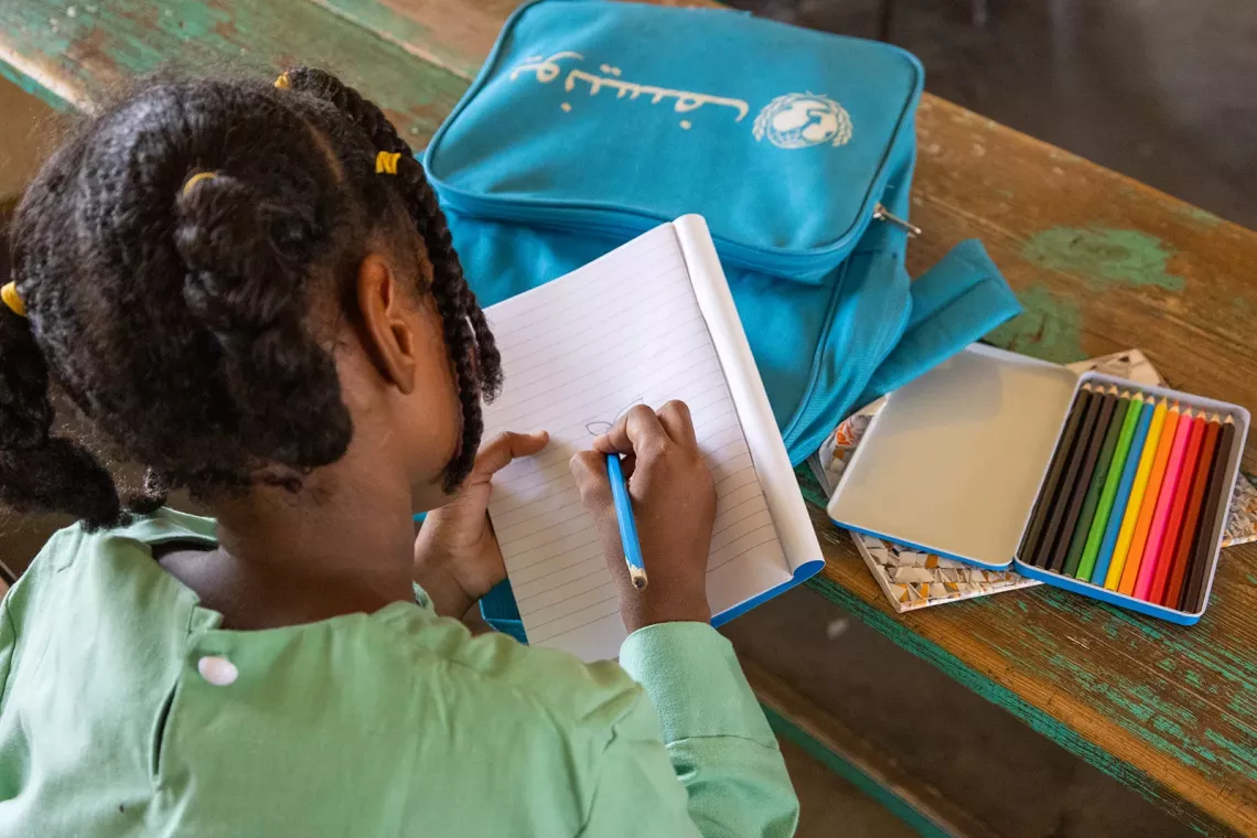 Wisam drawing a flower in her notebook.