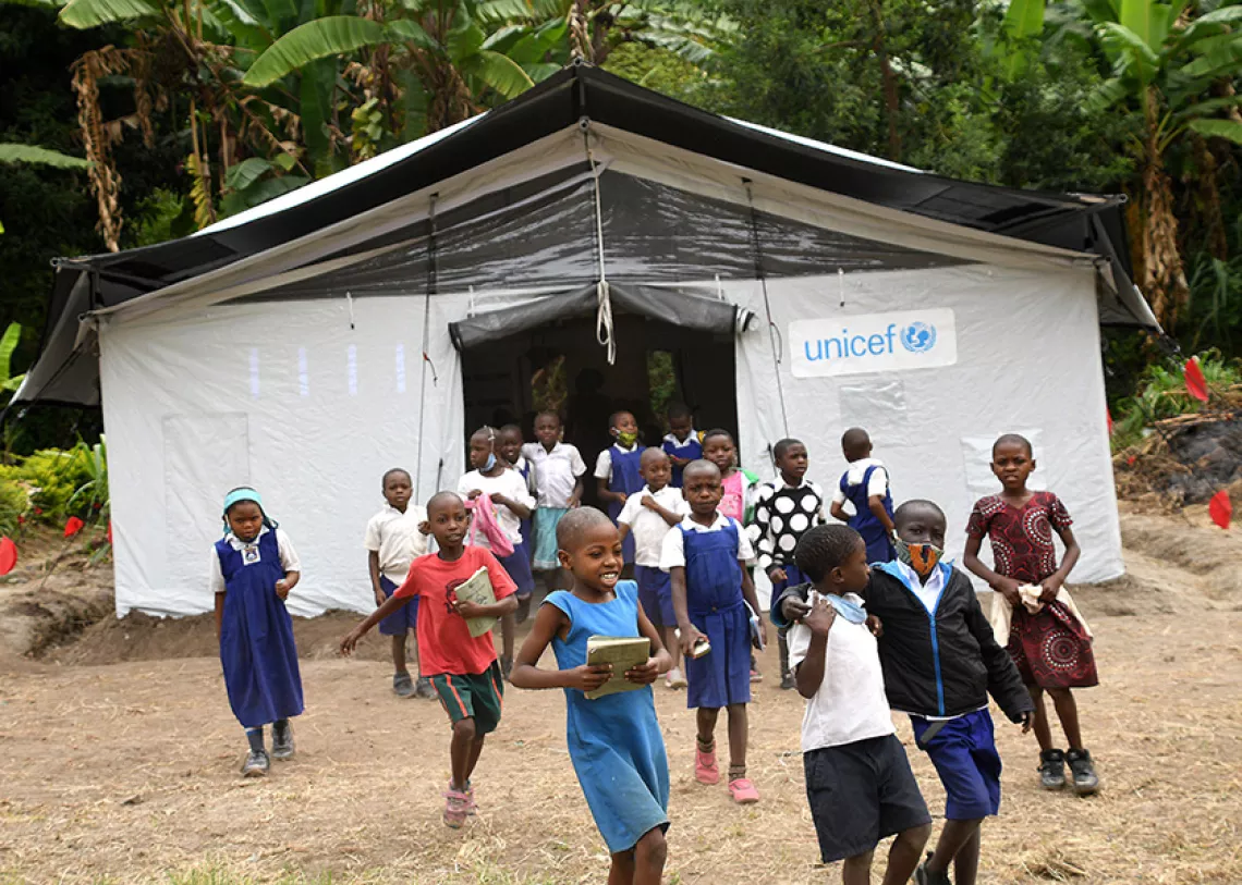Children leaving a school tent together. 