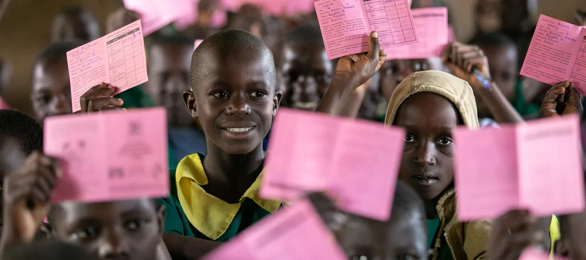 Children display their pink immunization cards after mass immunization at Aguket primary School in Aguket Village, Busia District, Uganda, in October 2019. 