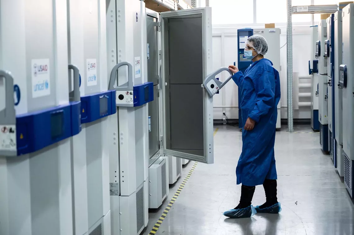 A health worker wearing personal protective equipment closes the door of a ultra-cold freezer provided to Ukraine by the United States Government through COVAX.