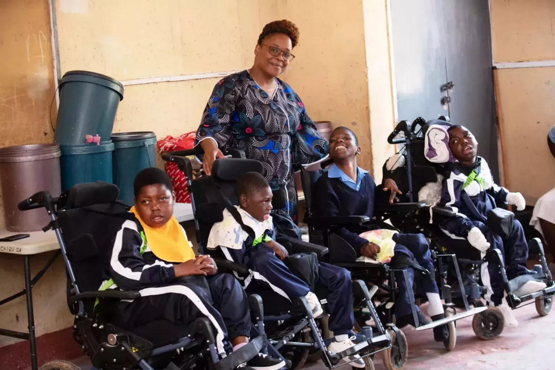 Teacher stands with differently-abled students. 