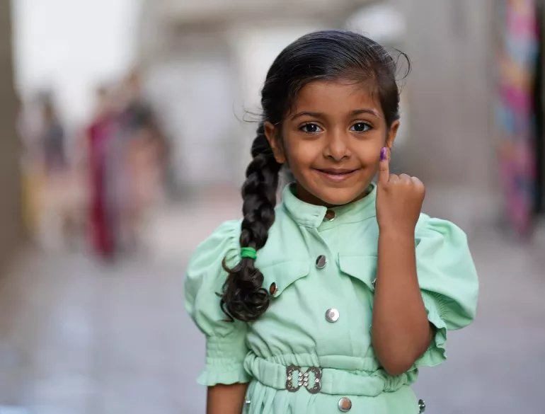 A young girl beams with pride as she displays her marked finger after being vaccinated against polio in Yemen.