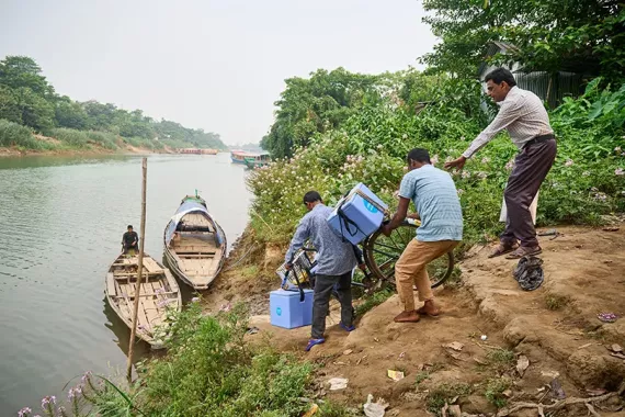 Health workers loading a canoe with vaccine carriers.