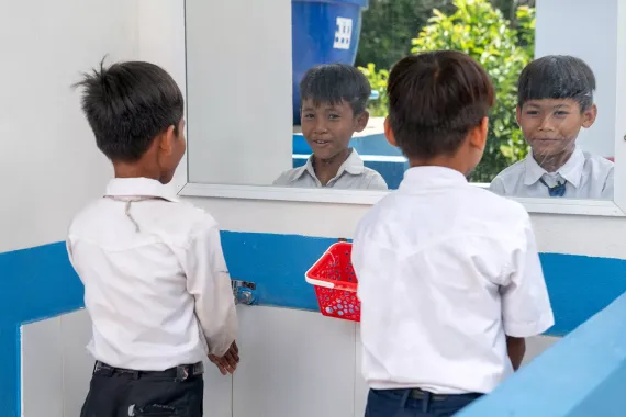 Two male students wash their hands.