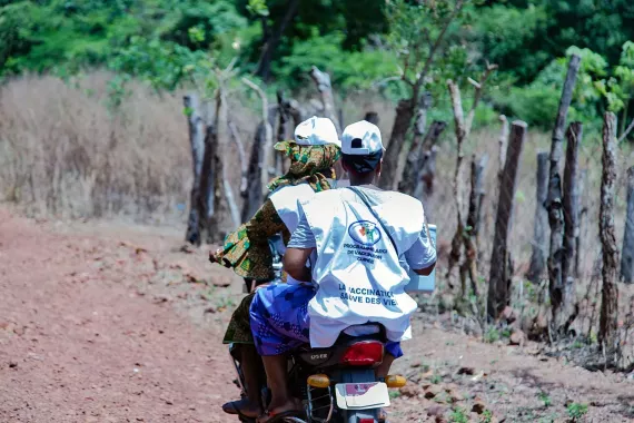 Two women on a motorbicile on a unpaved road. 