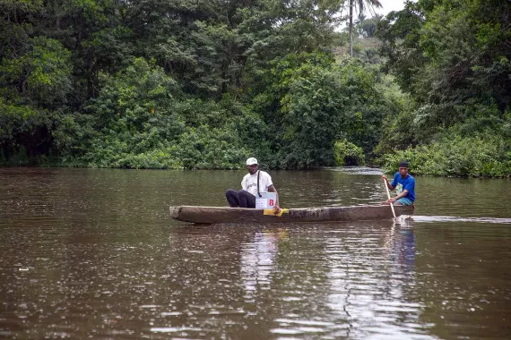 Two men crossing a river on a dugout canoe. 