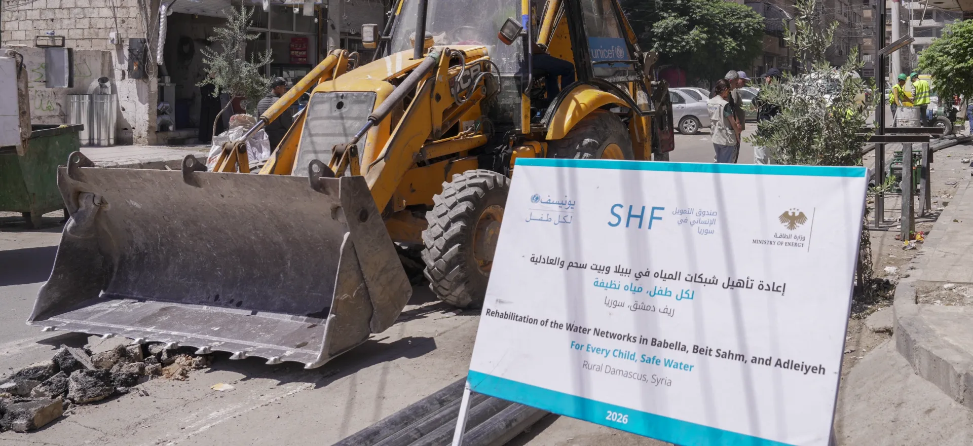 A large yellow bulldozer looms next to a large signboard.
