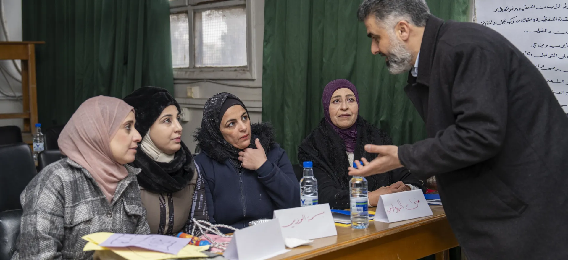 A man speaks to four women who are sitting behind a table.