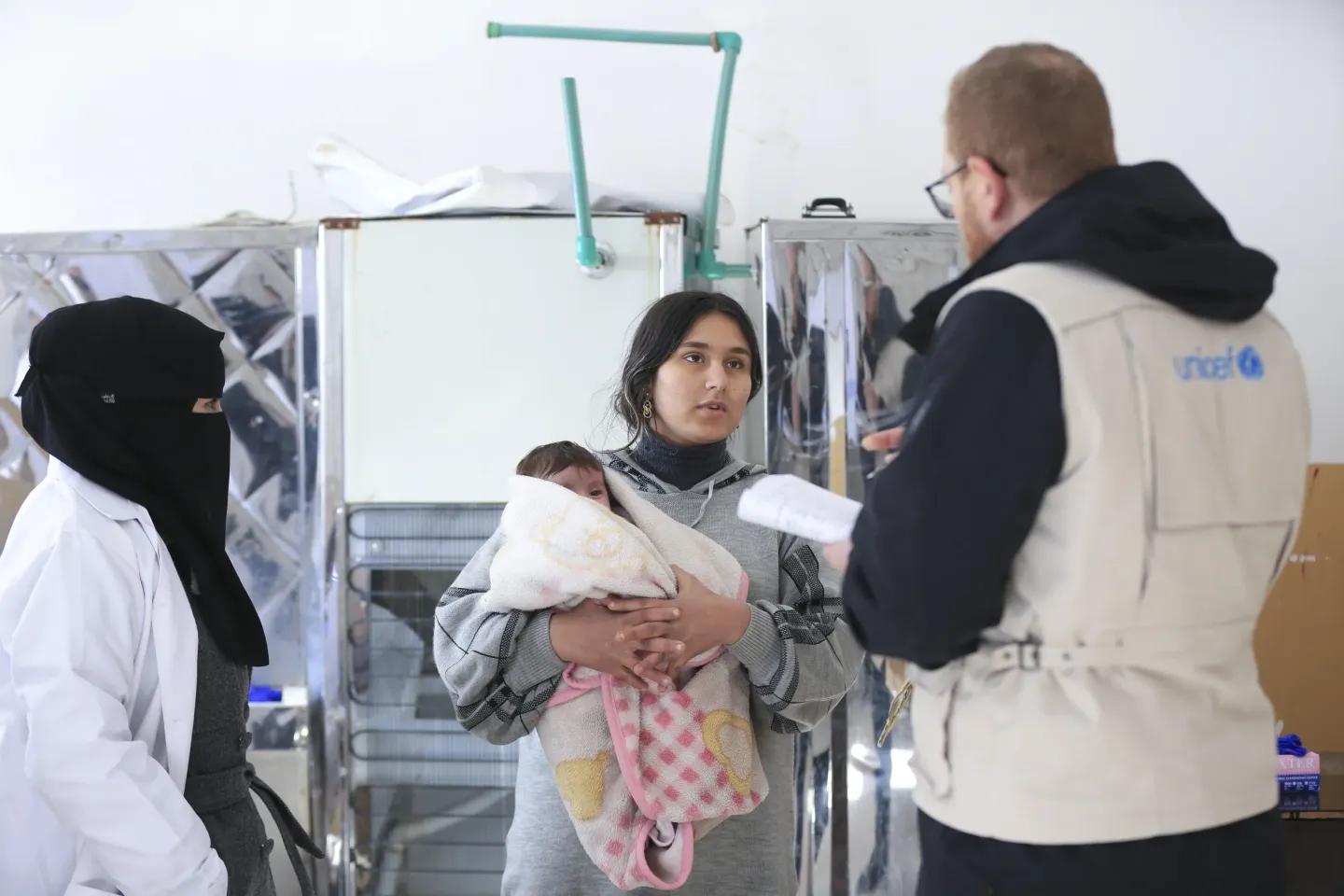UNICEF health workers listen to a woman holding a baby.