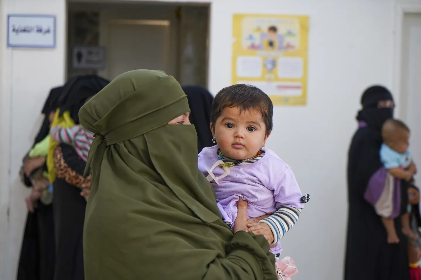 A woman holds a baby girls dressed in lilac.