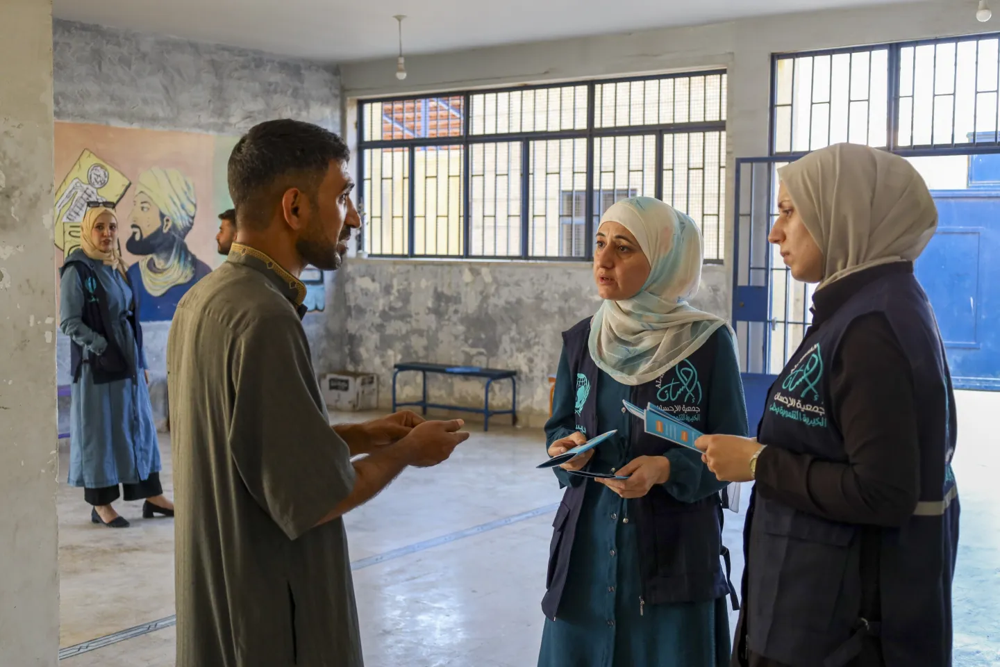 UNICEF-supported workers share brochures that introduce inclusive schools and explain the registration process, helping families, especially returnees and those with children with disabilities, access education, at Jameel Mishalah school, in Aleppo city.