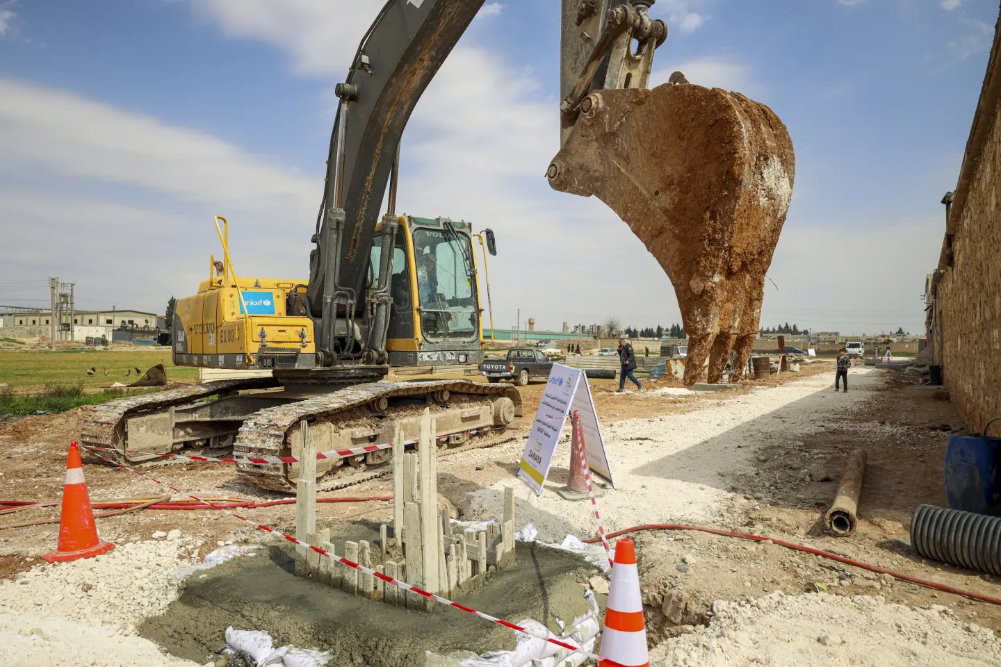 Formwork preparation for a reinforced concrete manhole with a huge excavator looming over it. 