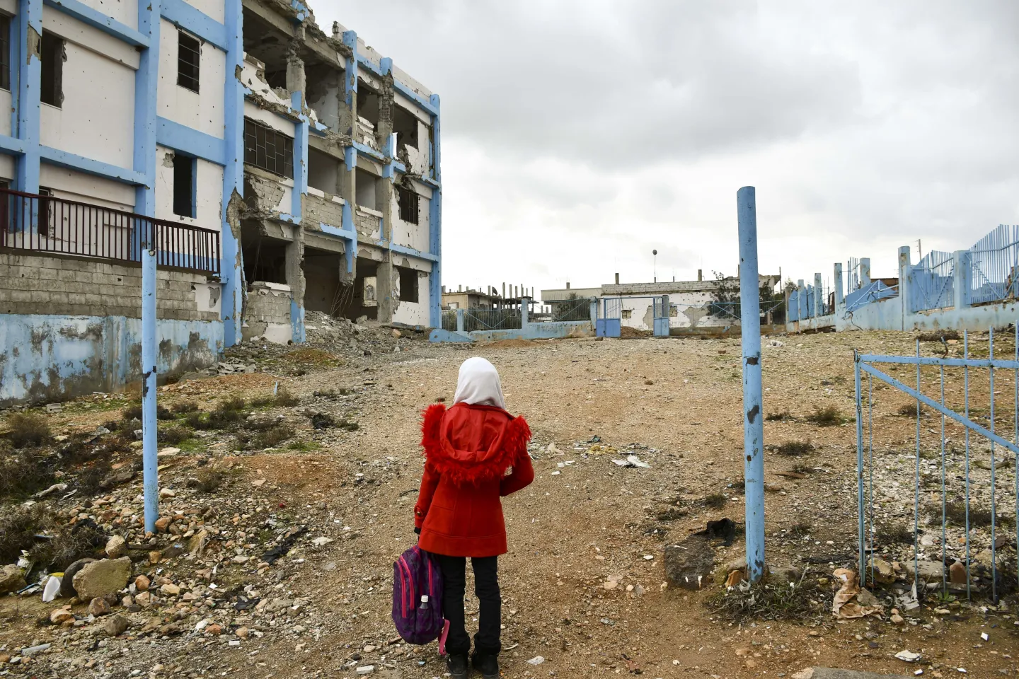 girl standing in front of destroyed school