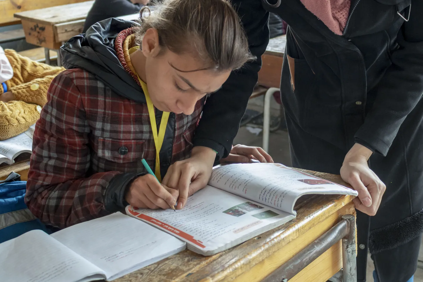 Girl writing on notebook in classroom